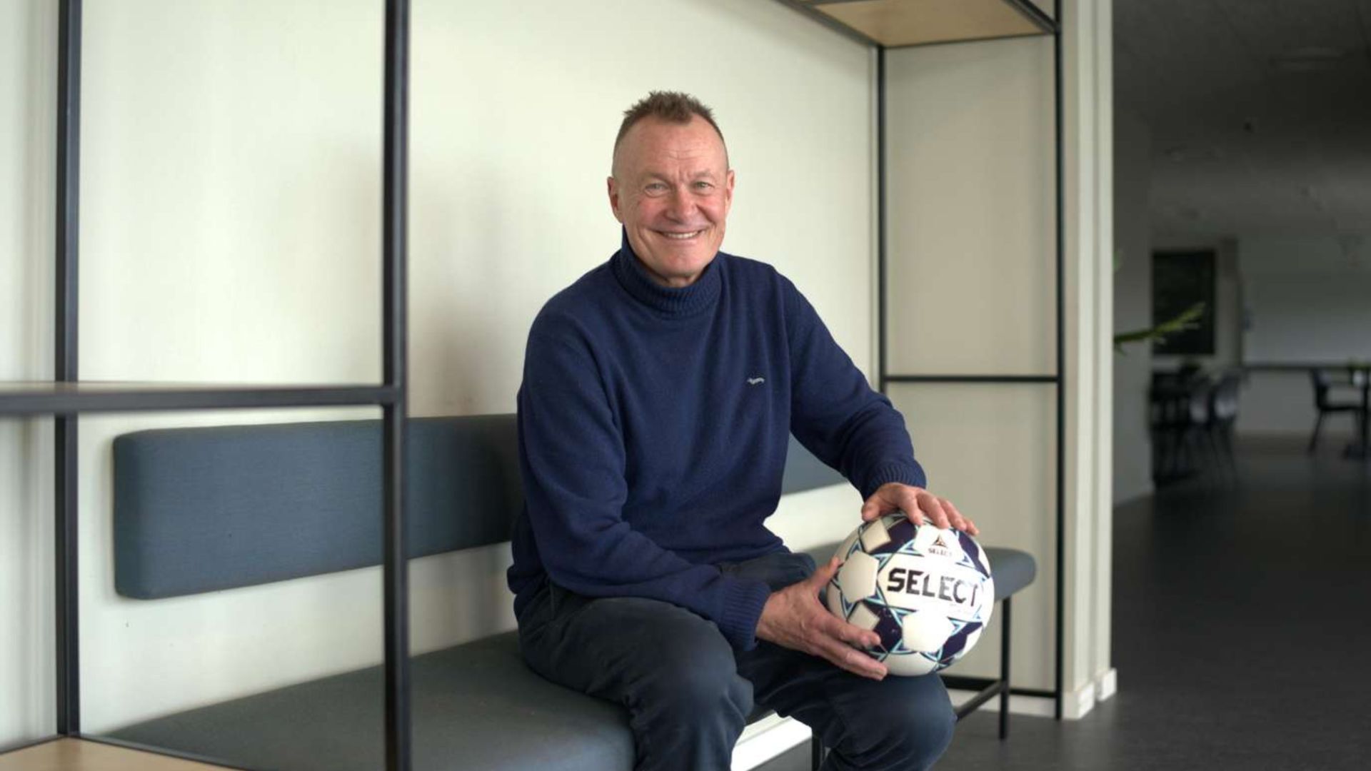 Per Frimann sidder på en bænk med en fodbold i hænderne