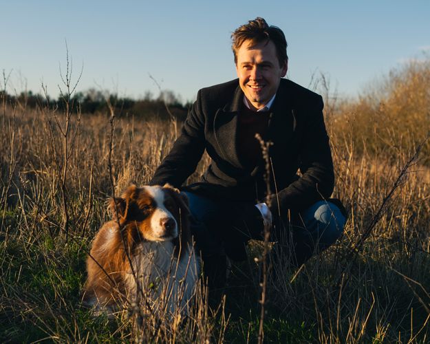 EU-parlamentariker Niels Fuglsang sidder i græs med hund ved sin side