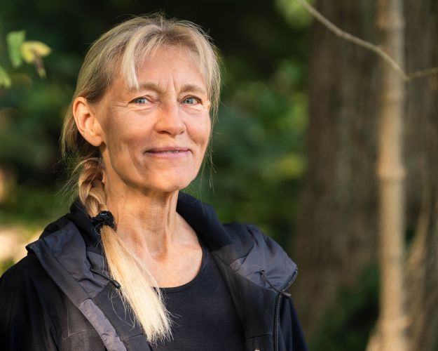 Maria Vang står i en skov og smiler til kameraet