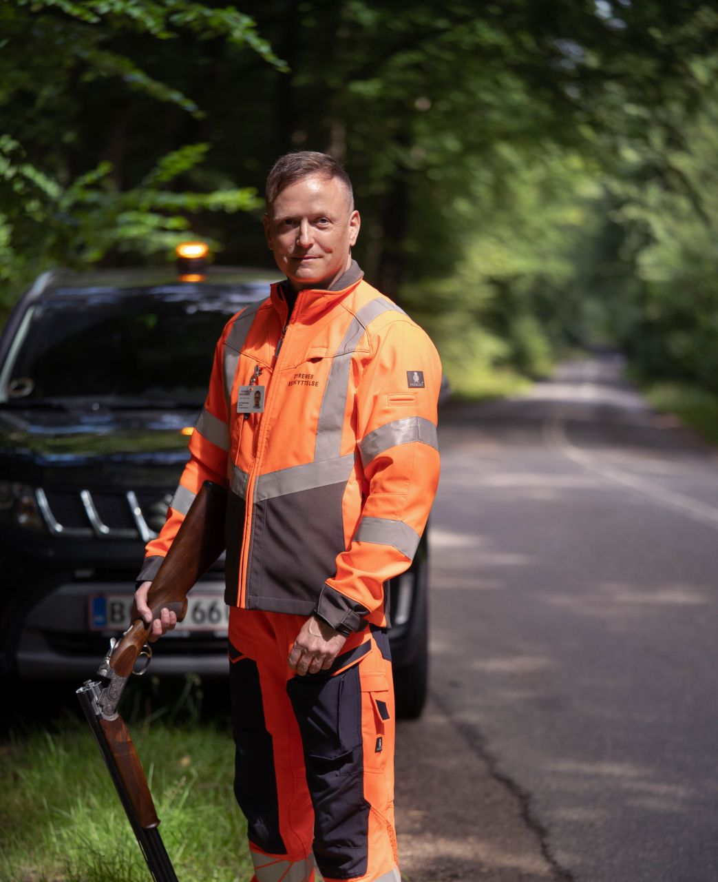skytte iklædt orange tøj står med jagtgevær i hånden