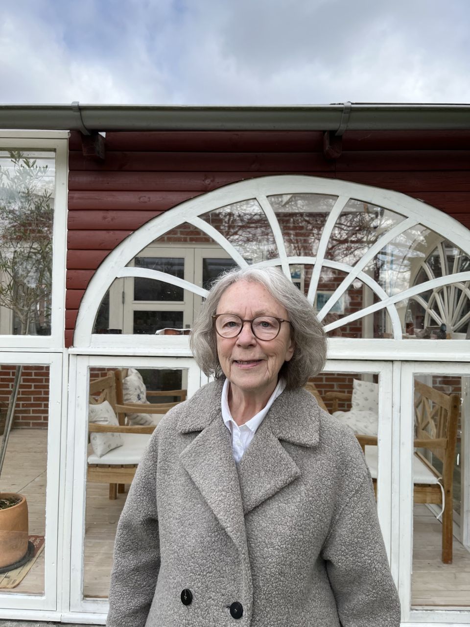 kvinde i grå jakke står foran vindue